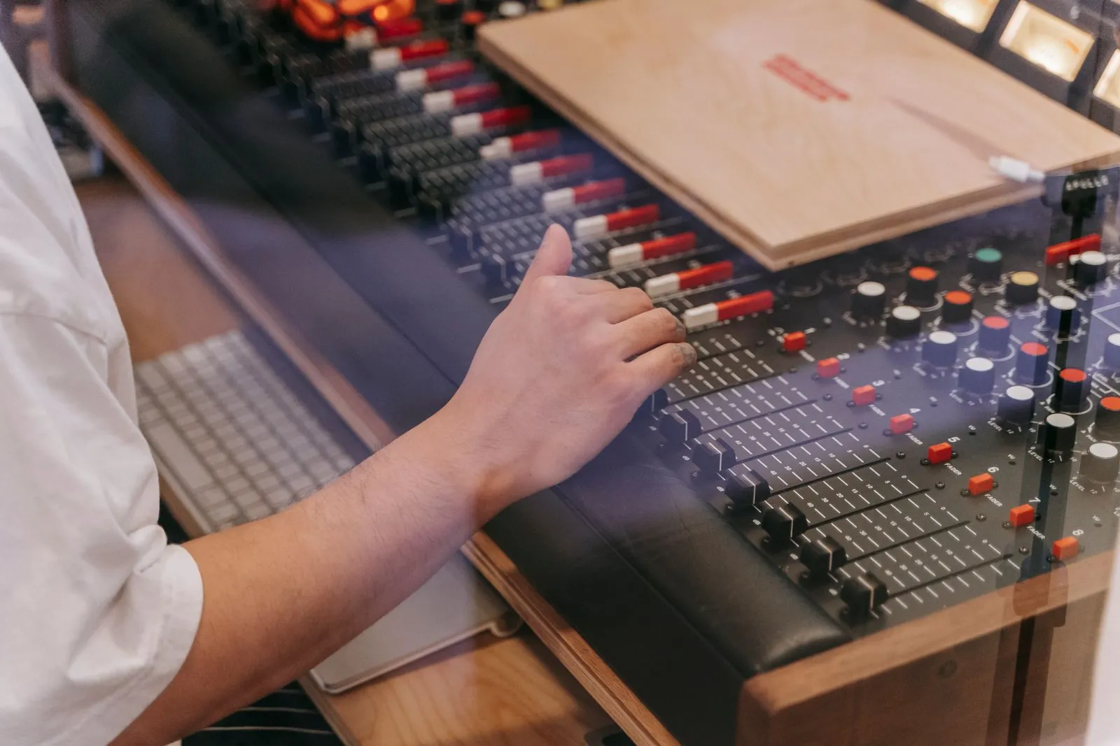 Close-up of an audio engineer's hand adjusting a mixing console in a recording studio.